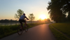 A person cycling on a park trail during sunrise