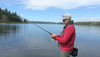 A beginner fishing near a peaceful lake with basic gear